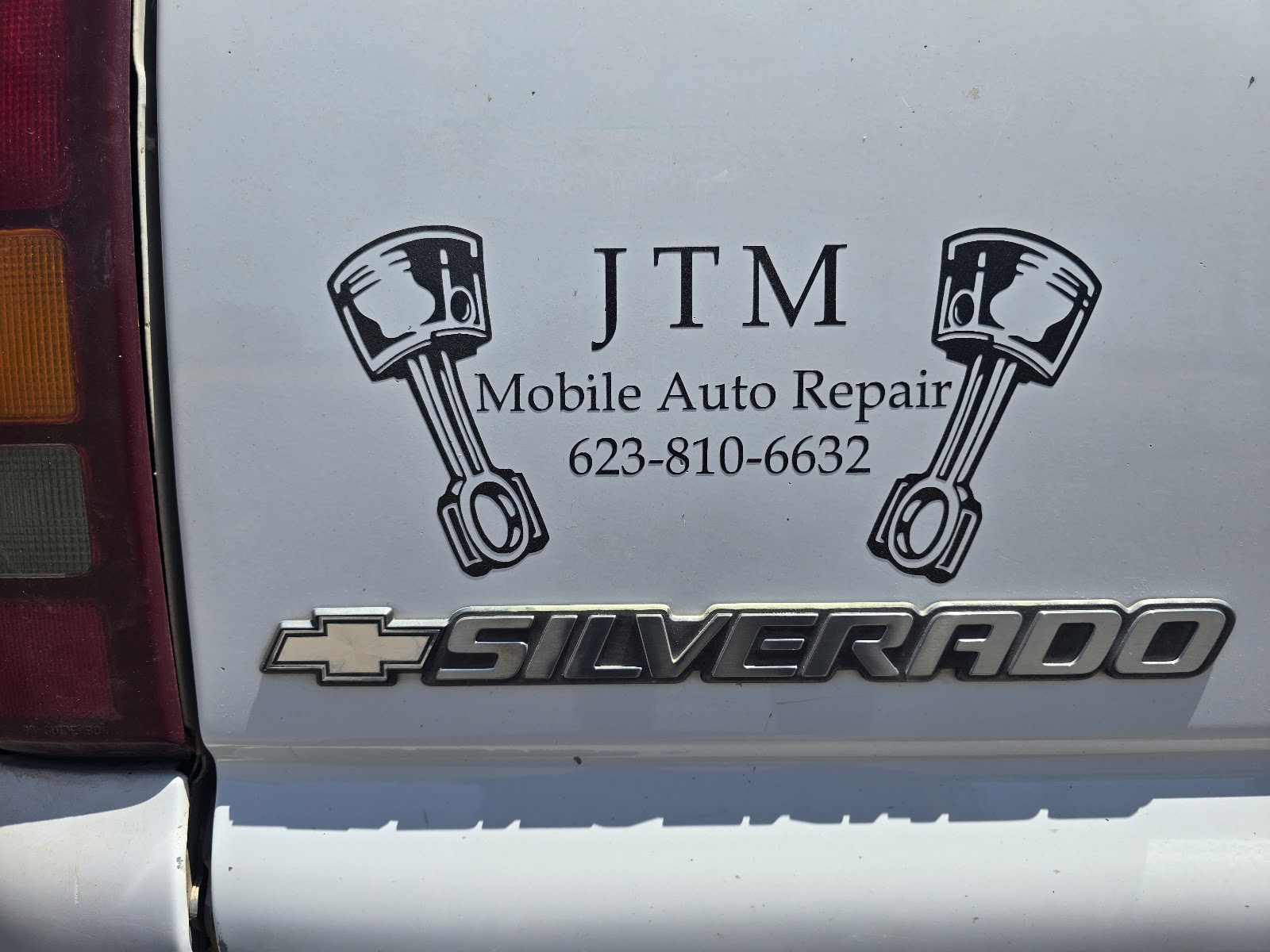White Silverado tailgate with the JTM Mobile Auto Repair decal: two pistons flanking the name and phone number
