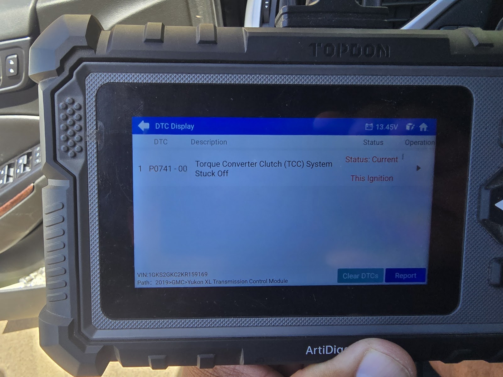 Diagnostic tablet held in hand, screen showing code P0741, Torque Converter Clutch System Stuck Off, on a GMC Yukon XL